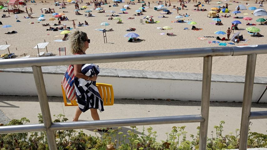 Pessoas passeiam à beira-mar na praia de Carcavelos, em Carcavelos, nos arredores de Lisboa, no sábado, 14 de agosto de 2021