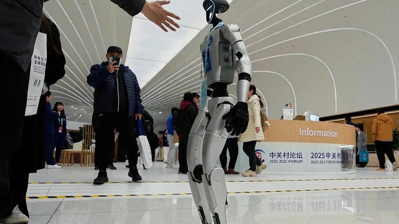 FICHEIRO: Um visitante estende a mão para cumprimentar um robô Unitree G1 no Fórum de Zhongguancun, no Centro Internacional de Zhongguancun