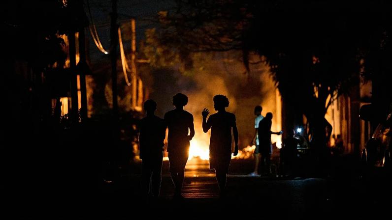 Pessoas caminham numa rua de Havana junto a uma fogueira acesa por moradores em protesto contra longos cortes de eletricidade