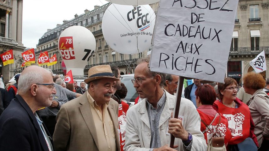Manifestante reformado segura um cartaz onde se lê "chega de presentes aos ricos" durante uma manifestação em Paris, França, quinta-feira, 14 de junho de 2018