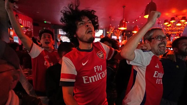 Adeptos do Arsenal festejam enquanto assistem num pub perto do estádio ao jogo da Premier League entre Bournemouth e Manchester City num pub perto do estádio do Arsenal, em Londres, a 19 de maio de 2026