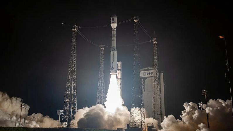 Foto noturna do foguetão Vega-C com a missão SMILE na plataforma de lançamento, rodeado por quatro pilares metálicos e nuvens de fumo
