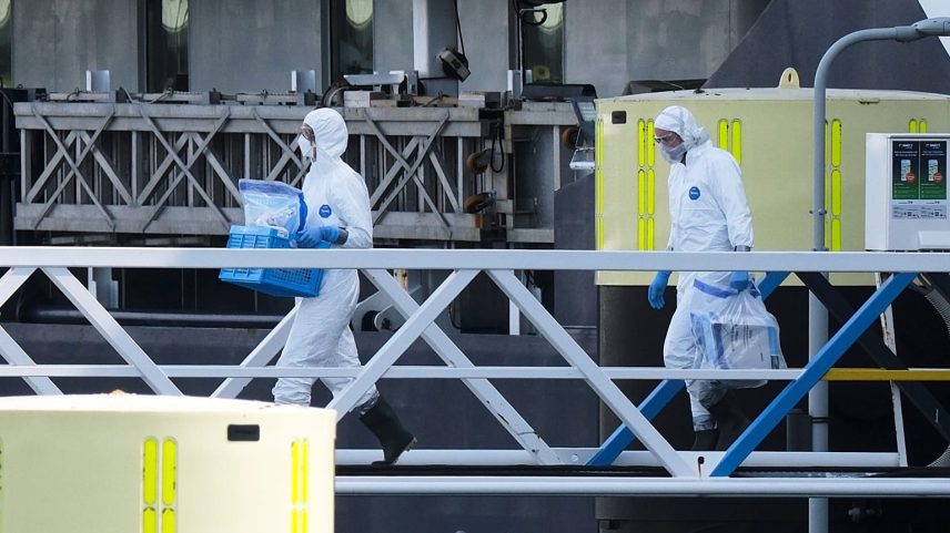 Pessoas com proteção transportam objetos não identificados ao desembarcarem do cruzeiro MV Hondius, no porto de Roterdão, Países Baixos, 18 de maio de 2026