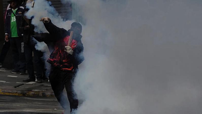 Manifestante devolve granada de gás lacrimogéneo à polícia durante protesto antigovernamental em La Paz, Bolívia, segunda-feira, 18 de maio de 2026