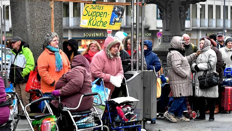 Os pobres merecedores esperam em filas atrás de uma placa onde se lê "Soup Kitchen" para receber comida gratuita na cidade velha de Colónia, Alemanha, sexta-feira, 11 de novembro de 2016.