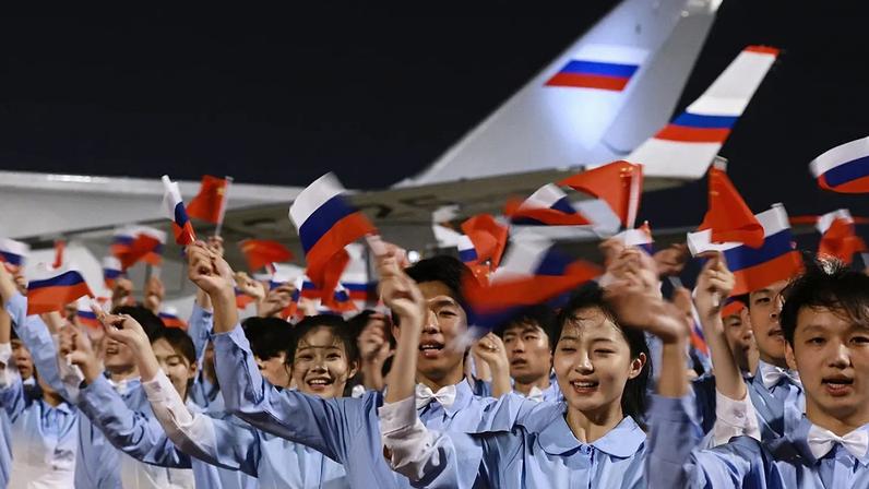 Jovens chineses recebem o presidente russo Vladimir Putin à chegada a Pequim, terça-feira, 19 de maio de 2026