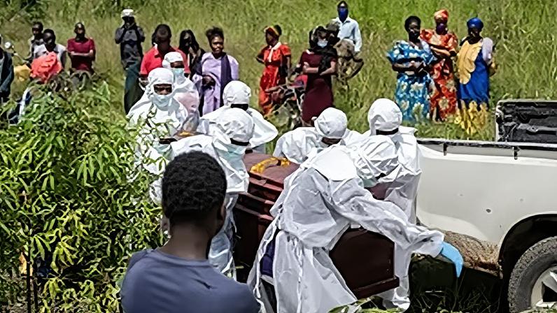 Trabalhadores da Cruz Vermelha preparam um caixão com o corpo de uma vítima de Ébola para sepultura no cemitério de Rwampara, em Bunia, Congo, sábado, 23 de maio de 2026.