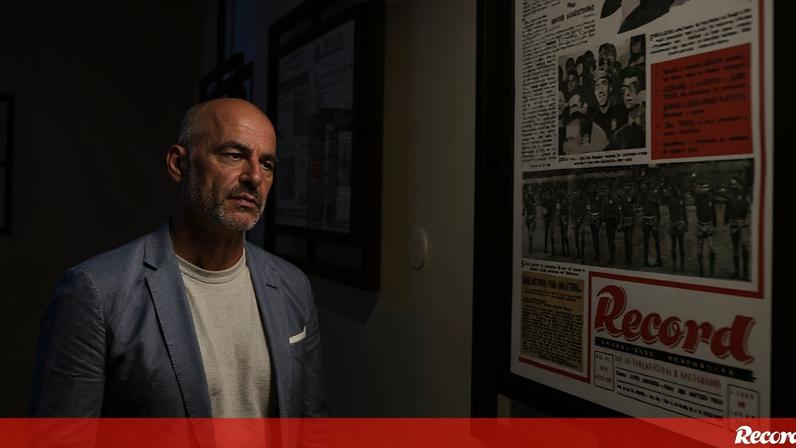 Homem observa capas do jornal Record numa exposição