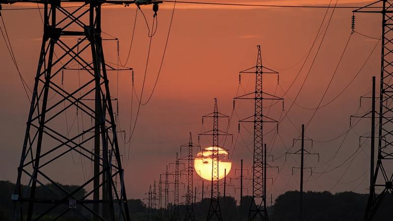 Linhas de alta tensão em frente a um pôr do sol.