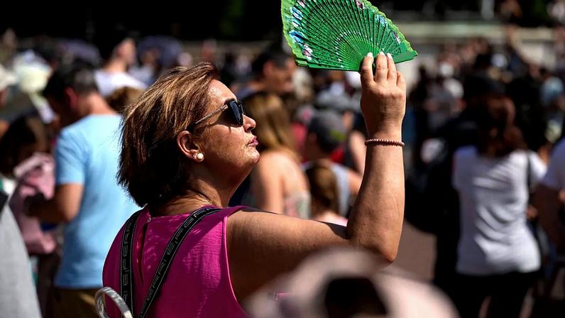 ARQUIVO – Uma turista protege o rosto do sol com um leque enquanto espera para ver a troca da guarda em frente ao Palácio de Buckingham, num dia de calor em Londres.
