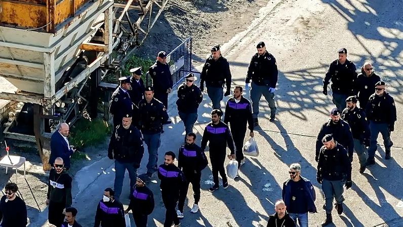 Migrantes caminham no porto de Shengjin, na Albânia, depois de desembarcarem de um navio da Marinha italiana. Itália construiu dois centros de deportação no país
