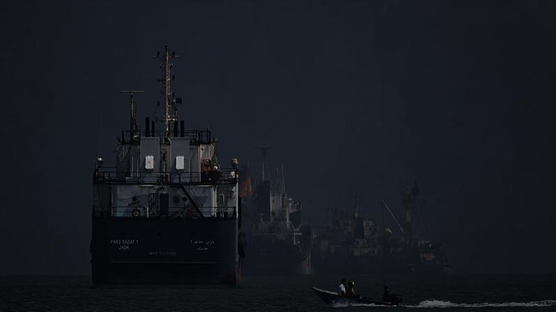 Pequena lancha a motor passa por navios fundeados no estreito de Ormuz, ao largo de Bandar Abbas, Irão, quinta-feira, 11 de junho de 2026