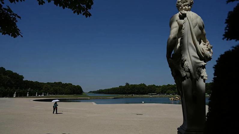 Mulher protege-se do sol com um guarda-chuva enquanto passeia nos jardins do Palácio de Versalhes durante uma onda de calor com temperaturas acima dos 40 ºC