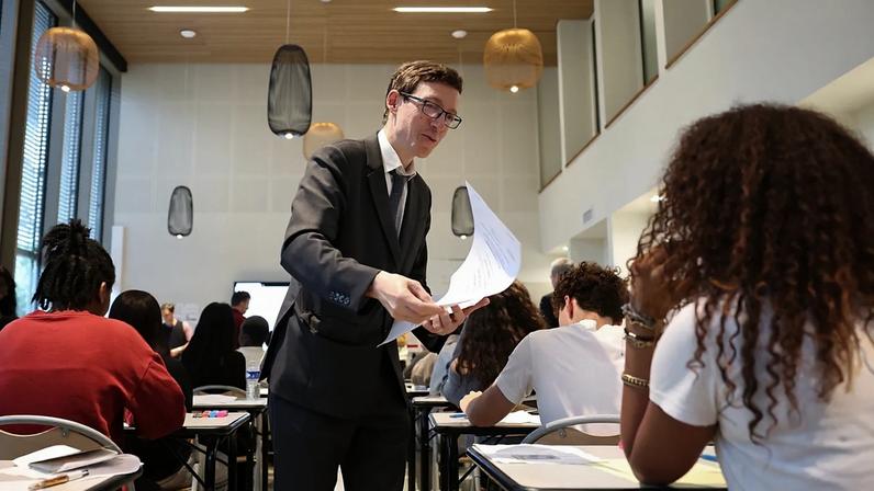 O ministro francês da Educação, Edouard Geffray, ao centro, distribui aos alunos o exame de Matemática na escola e colégio Gabriel Faure, em Paris, 12 de junho de 2026.