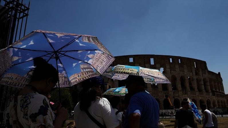 FILE: Turistas usam guarda-chuvas para se proteger do calor enquanto aguardam na fila para uma visita ao Fórum, em Roma, terça-feira, 22 de julho de 2025.