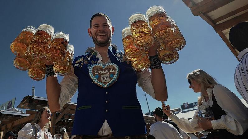 Um empregado de mesa transporta canecas de cerveja para a tenda Hacker no primeiro dia da Oktoberfest, na Theresienwiese, em Munique, Alemanha, sábado, 20 set. 2025