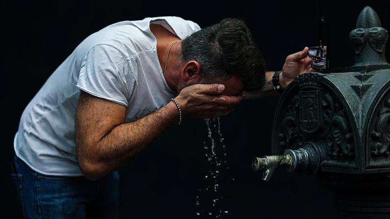 ARQUIVO - Um homem refresca-se numa fonte num dia de verão quente e soalheiro em Madrid, Espanha, em 19 de julho de 2023.