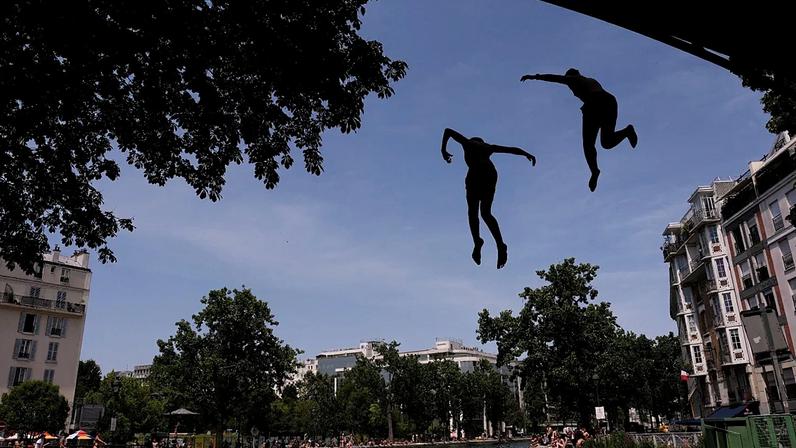 Parisienses tomam banho no canal Saint-Martin, em Paris, enquanto o serviço meteorológico Météo France coloca 54 departamentos em alerta vermelho, 23 de junho de 2026