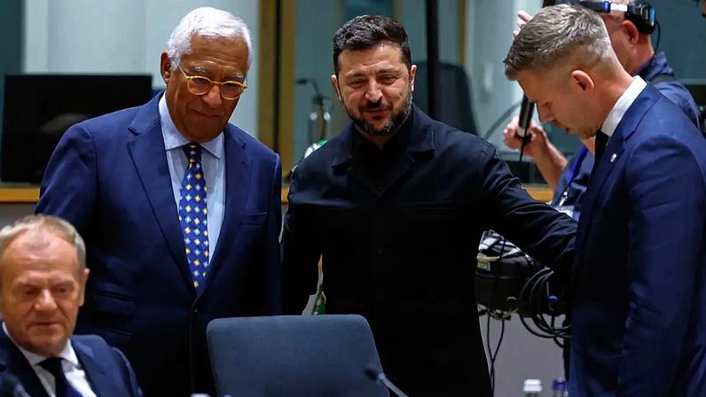 Volodymyr Zelensky cumprimenta o primeiro-ministro húngaro Peter Magyar, ao lado do presidente do Conselho Europeu António Costa, na cimeira da UE em Bruxelas, 18.06.2026