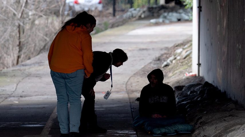 Elementos da equipa de apoio Resiliency Empowerment Support Team (REST) falam com uma pessoa sem-abrigo que dorme debaixo de uma ponte em Chico, Califórnia