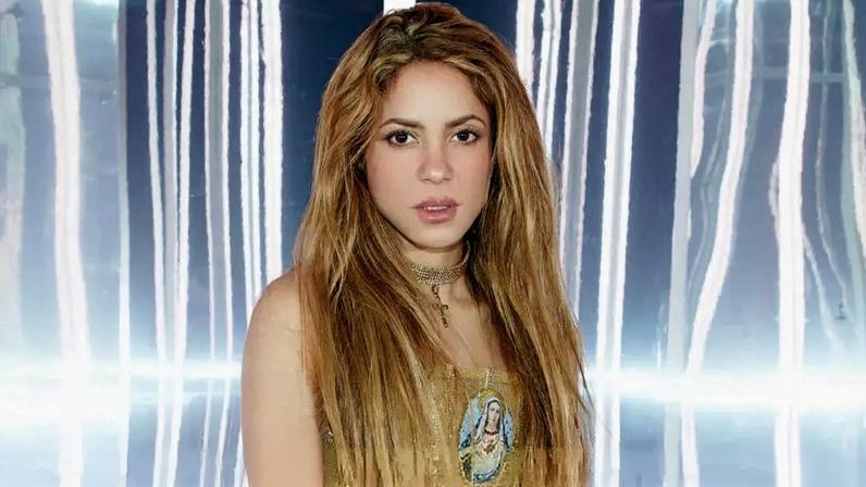 Shakira veste um vestido dourado com imagem religiosa e saltos altos