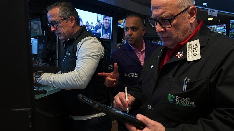 Especialistas Glenn Carell e Dilip Patel trabalham com o operador Jeffrey Vazquez na bolsa de Nova Iorque, 26 de junho de 2026