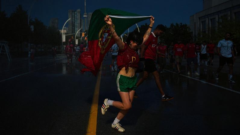 Um adepto português corre por um jato de água, enquanto os adeptos tentam refrescar-se antes do jogo dos 16-avos do Mundial 2026 entre Portugal e Croácia